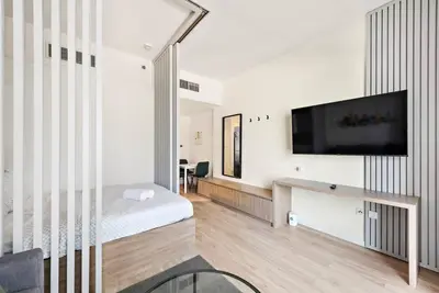 a white room with a bed and a flat screen tv at Cozy Studio By Burj Khalifa and Dubai Mall in Dubai