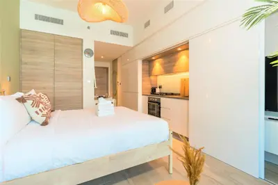 a bedroom with a white bed and a kitchen at Stunning Apt with Balcony & Marina View in Dubai