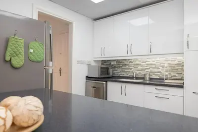 a kitchen with white cabinets and a black counter top at StoneTree - Spacious 2BR in Great Location in Dubai