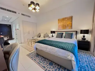 a bedroom with a large bed and a living room at Ghalia Damac Studio Apartment in Dubai