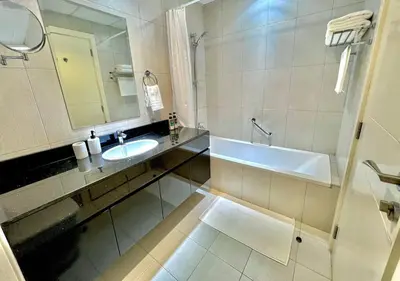 a bathroom with a sink and a mirror and a tub at Ghalia Damac Studio Apartment in Dubai