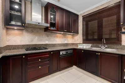 a kitchen with dark wood cabinets and a sink at Lux BnB I Souk Al Bahar I Burj Khalifa Views in Dubai
