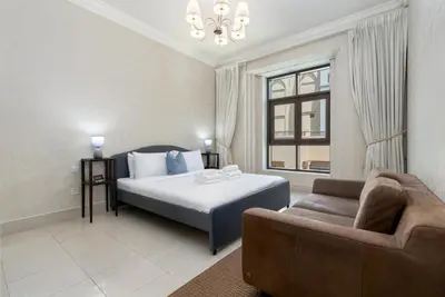 a bedroom with a bed and a couch and a window at Lux BnB I Souk Al Bahar I Burj Khalifa Views in Dubai
