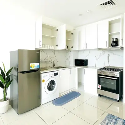a kitchen with a refrigerator and a washing machine at Stylish Studio For Two in Dubai