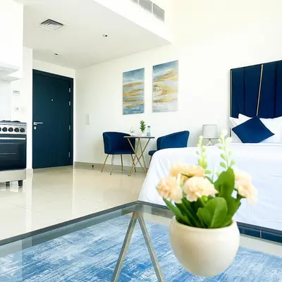 a living room with a table and a vase with flowers at Stylish Studio For Two in Dubai