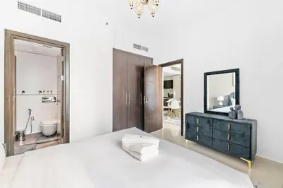 a white bedroom with a bed and a mirror at StoneTree - Elegant 1BR with Amazing Building Facilities in Dubai