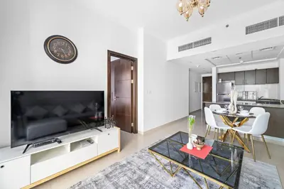 a living room with a television and a table and chairs at StoneTree - Elegant 1BR with Amazing Building Facilities in Dubai