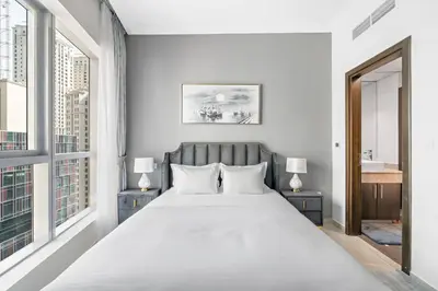 a white bedroom with a large bed and windows at StoneTree - Elegant 1BR with Amazing Building Facilities in Dubai