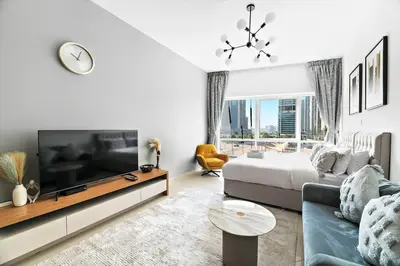 a white living room with a bed and a tv at StoneTree - Best Deal - Elegant Studio in Dubai