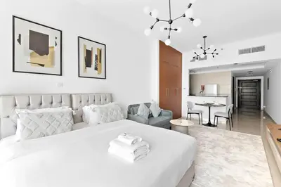 a white bedroom with a large bed and a living room at StoneTree - Best Deal - Elegant Studio in Dubai