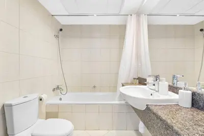 a bathroom with a toilet and a sink and a tub at StoneTree - Best Deal - Elegant Studio in Dubai