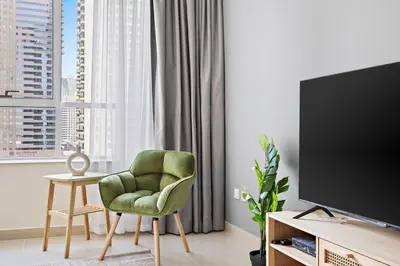 a living room with a green chair and a television at StoneTree - Sit Back, Relax and Your New View Awaits in Dubai