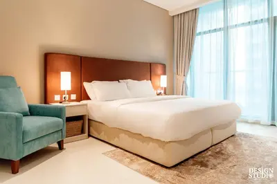 a bedroom with a large bed and a blue chair at SEVEN PALM by Design Studio 2BR in Dubai