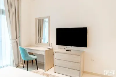 a bedroom with a tv and a desk and a chair at SEVEN PALM by Design Studio 2BR in Dubai