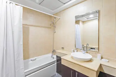 a bathroom with a sink and a tub and a mirror at StoneTree - Elegant 1BR in Famous Location in Dubai