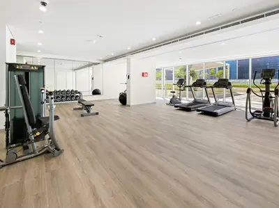 a gym with several treadmills and machines in a room at StoneTree - Modern 1BR Apartment in Vera Residence in Dubai
