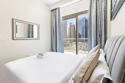 a bedroom with a bed and a large window at StoneTree - Modern 1BR Apartment in Vera Residence in Dubai