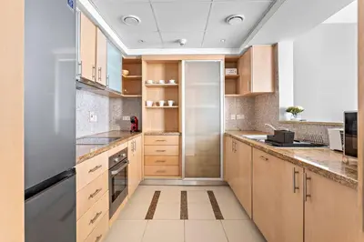 a kitchen with wooden cabinets and stainless steel appliances at StoneTree - Stylish fully-furnished 1 BR in Dubai