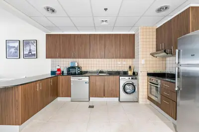 a large kitchen with wooden cabinets and a dishwasher at StoneTree - High Floor Furnished 1 BR in Dubai