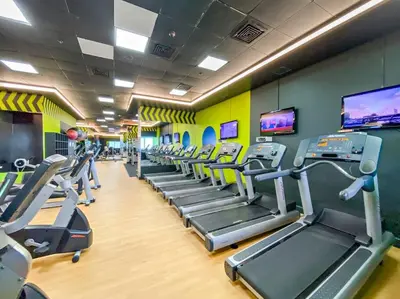 a gym with rows of tread machines and televisions at StoneTree - High Floor Furnished 1 BR in Dubai