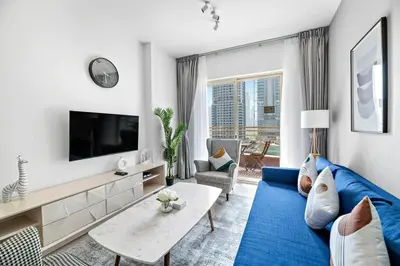 a living room with a blue couch and a tv at StoneTree - Furnished 1BR with Stunning View in Dubai