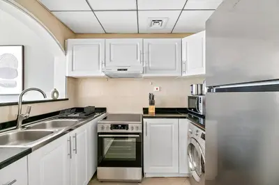 a kitchen with white cabinets and a sink and a dishwasher at StoneTree - Furnished 1BR with Stunning View in Dubai