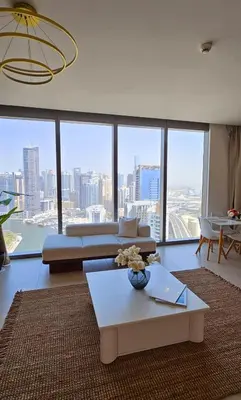 a living room with a couch and a table and a large window at Amazing 4-bedroom Apartment in Dubai