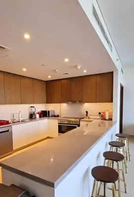 a large kitchen with a counter and stools in it at Amazing 4-bedroom Apartment in Dubai