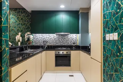 a kitchen with green cabinets and a stove at Luxury Apartments with Rooftop Pool in Paramount Hotel Midtown By Aurora in Dubai