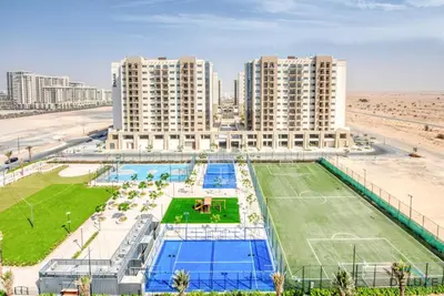 an apartment complex with a tennis court in front of a beach at Immaculate 1BR at UNA Town Square Dubailand by Deluxe Holiday Homes in Dubai