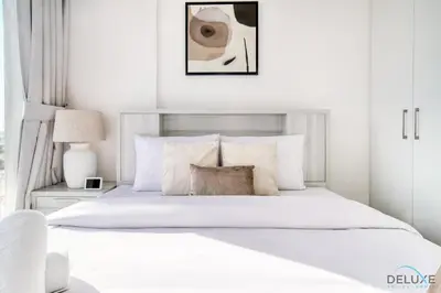 a white bedroom with a large bed with white pillows at Immaculate 1BR at UNA Town Square Dubailand by Deluxe Holiday Homes in Dubai