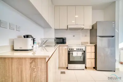 a kitchen with white cabinets and stainless steel appliances at Immaculate 1BR at UNA Town Square Dubailand by Deluxe Holiday Homes in Dubai