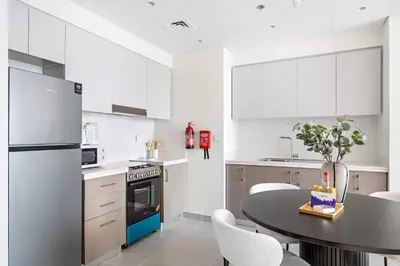 a kitchen with white cabinets and a table with chairs at Silkhaus classical 1BDR in Opera District in Dubai