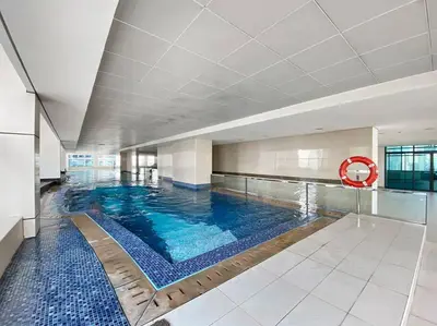 a large swimming pool with blue water in a building at StoneTree - Chic & Modern 1BR in Dubai