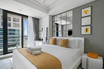 a bedroom with a large white bed with a large window at StoneTree - Modern Furnished Studio in Dubai