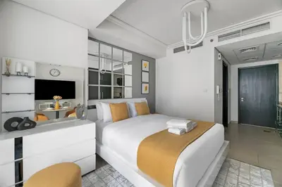 a white bedroom with a large bed and a tv at StoneTree - Modern Furnished Studio in Dubai