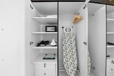 a closet with white shelves and a tie in it at StoneTree - Modern Furnished Studio in Dubai