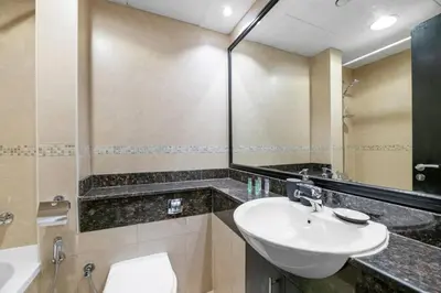 a bathroom with a sink and a toilet and a mirror at StoneTree - Modern Furnished Studio in Dubai