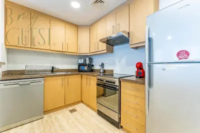 a kitchen with wooden cabinets and a refrigerator at Spacious Modern 1BR in Business Bay in Dubai