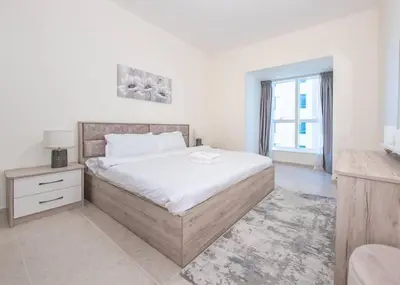 a white bedroom with a bed and a window at StoneTree - Near Tram - Furnished 1BR in Dubai