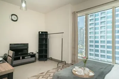 a living room with a tv and a large window at StoneTree - Lake View - Family-Friendly Location in Dubai