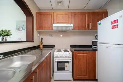a kitchen with wooden cabinets and a white refrigerator at StoneTree - Lake View - Family-Friendly Location in Dubai