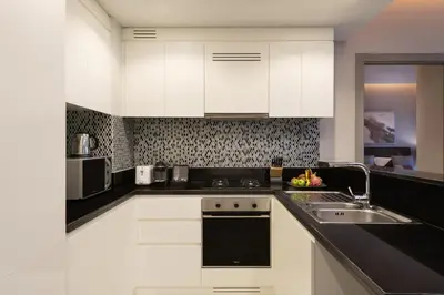 a kitchen with white cabinets and a sink at DAMAC Maison Aykon City Dubai in Dubai