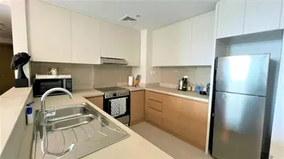 a kitchen with white cabinets and a stainless steel refrigerator at Luxurious Creek Harbour Apt with Balcony & View in Dubai