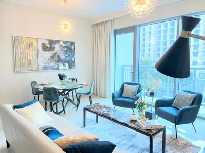 a living room with a couch and a table and chairs at Luxurious Creek Harbour Apt with Balcony & View in Dubai