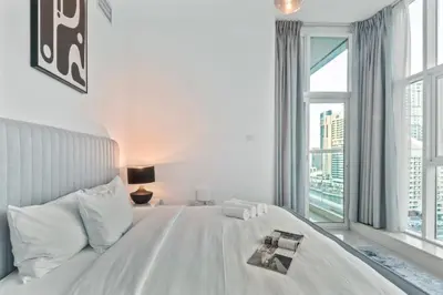a bedroom with a white bed with a large window at Cozy Heaven with full Marina View in Dubai