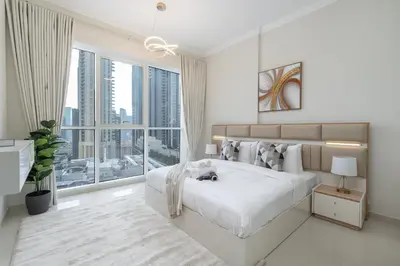 a white bedroom with a large bed and a large window at Heaven Crest Vacation Homes Downtown - Studio and 1 Bedroom Suites 2 minute walk to Dubai Mall and Burj Khalifa in Dubai