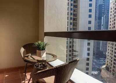 a balcony with two chairs and a table with a plant at StoneTree - Studio Apartment Near The Beach in Dubai