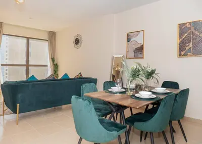 a dining room with a table and chairs and a couch at StoneTree - Studio Apartment Near The Beach in Dubai