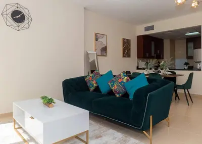 a living room with a green couch and a table at StoneTree - Studio Apartment Near The Beach in Dubai